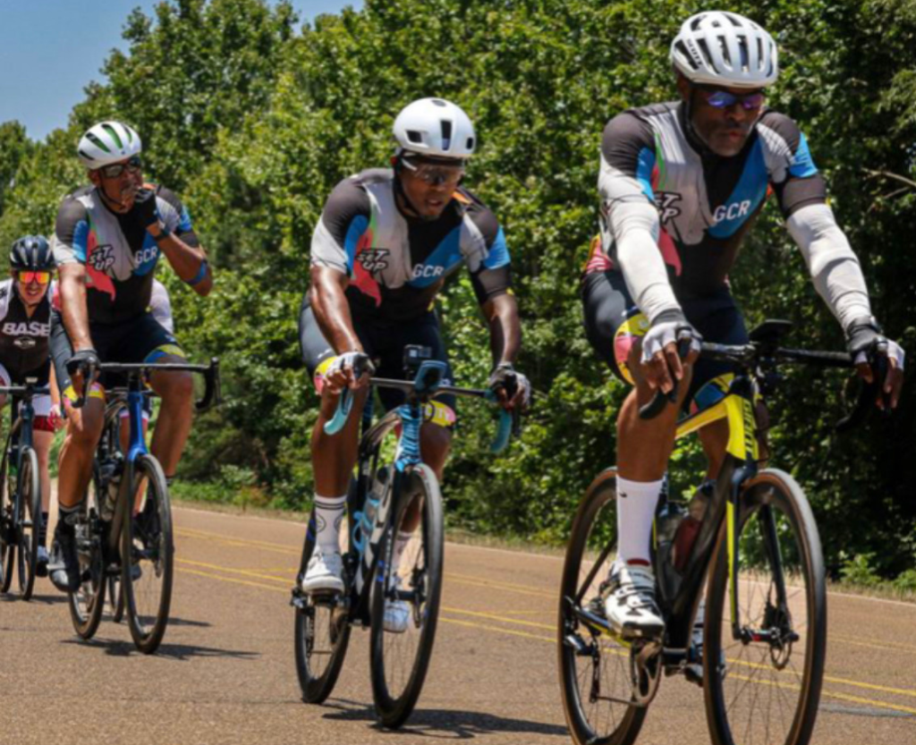An image of a bicycling team in a high-speed race. The cyclists, dressed in streamlined, colorful uniforms, are closely packed together, demonstrating teamwork and focus.